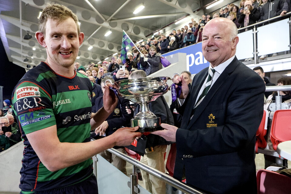 Clogher Valley captain Paul Armstrong receives the Energia All-Ireland Junior Cup from IRFU President John Robinson.
